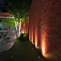 Full shot of a garden with ground lights lined across a brick wall