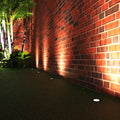 Side shot of a garden with ground lights lined across a brick wall