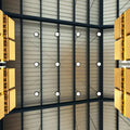 multiple LED high bay lights visible from the ground of the warehouse, some boxes on shelves are seen on both sides