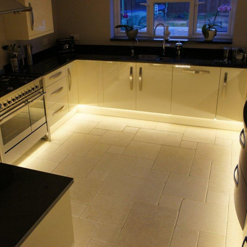 Mid shot of a kitchen cabinet with LED tape in warm white light at the bottom.